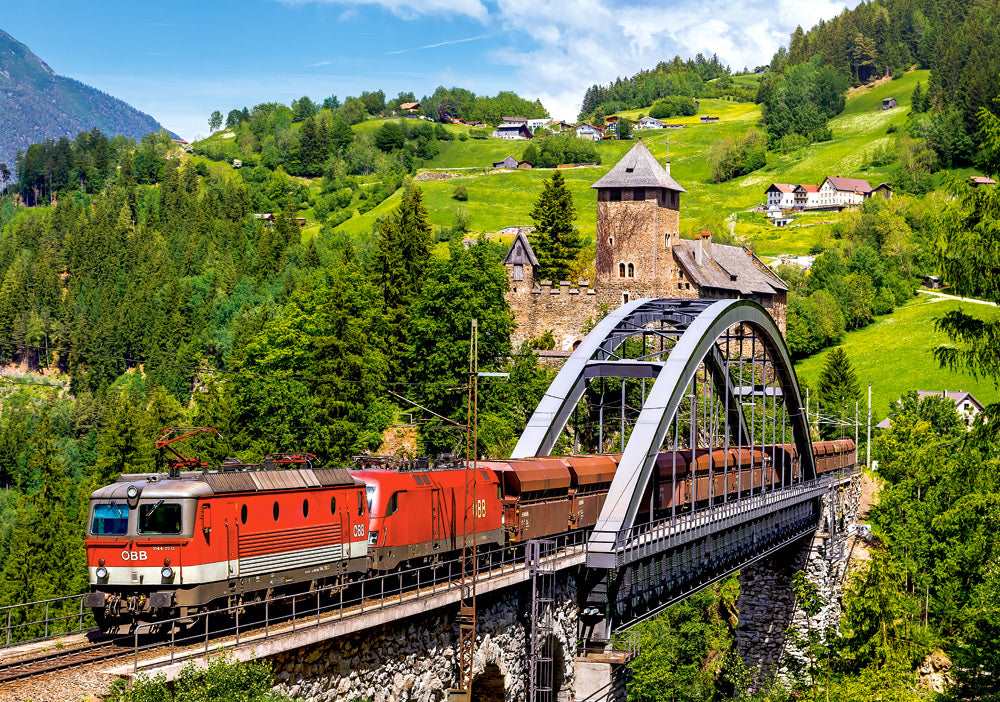 Passenger train crossing steel bridge in mountain landscape