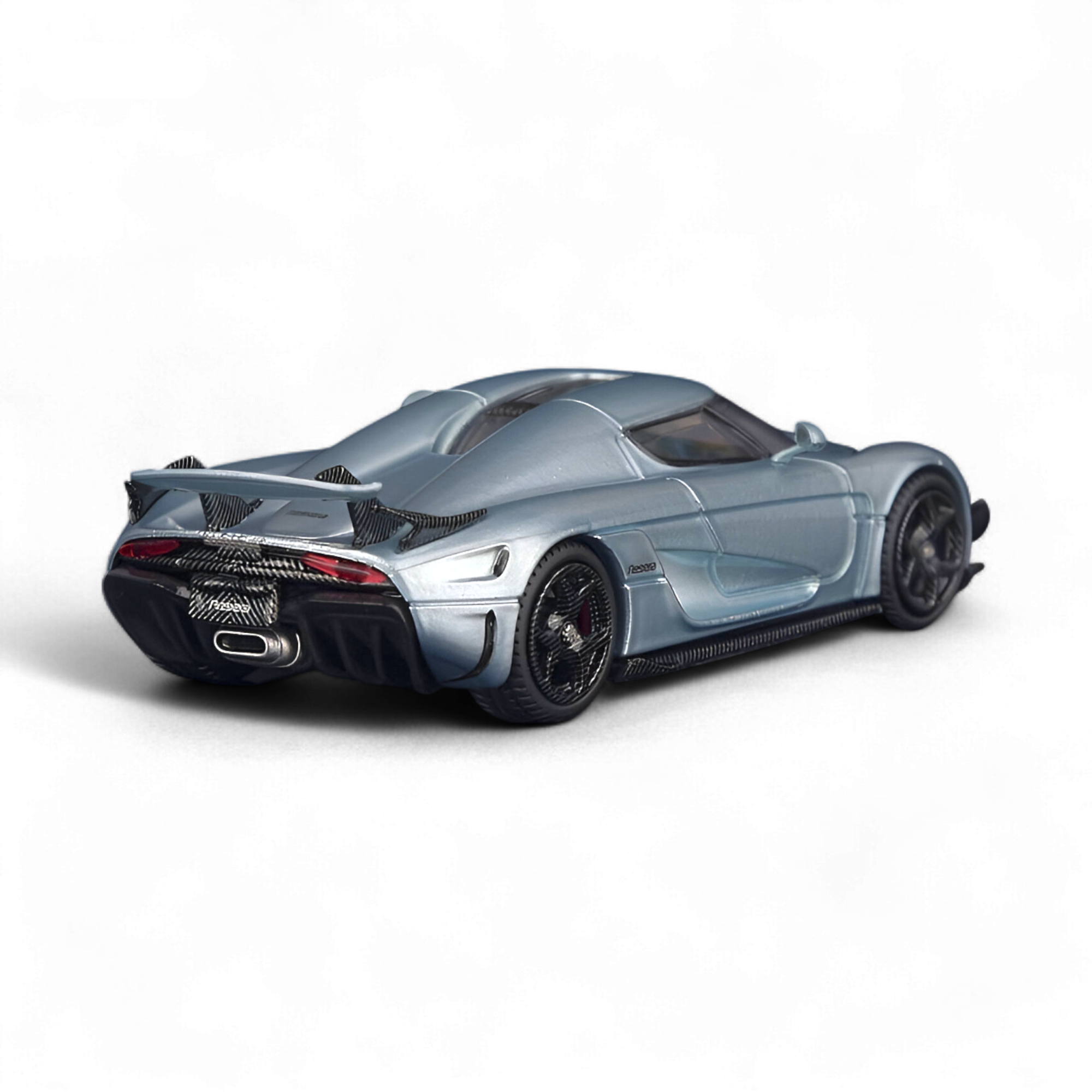 Rear three-quarter view of the SC ART Koenigsegg Regera Glacier Blue 1:64 diecast model showcasing the aerodynamic bodywork, rear wing, and detailed carbon fiber finish.