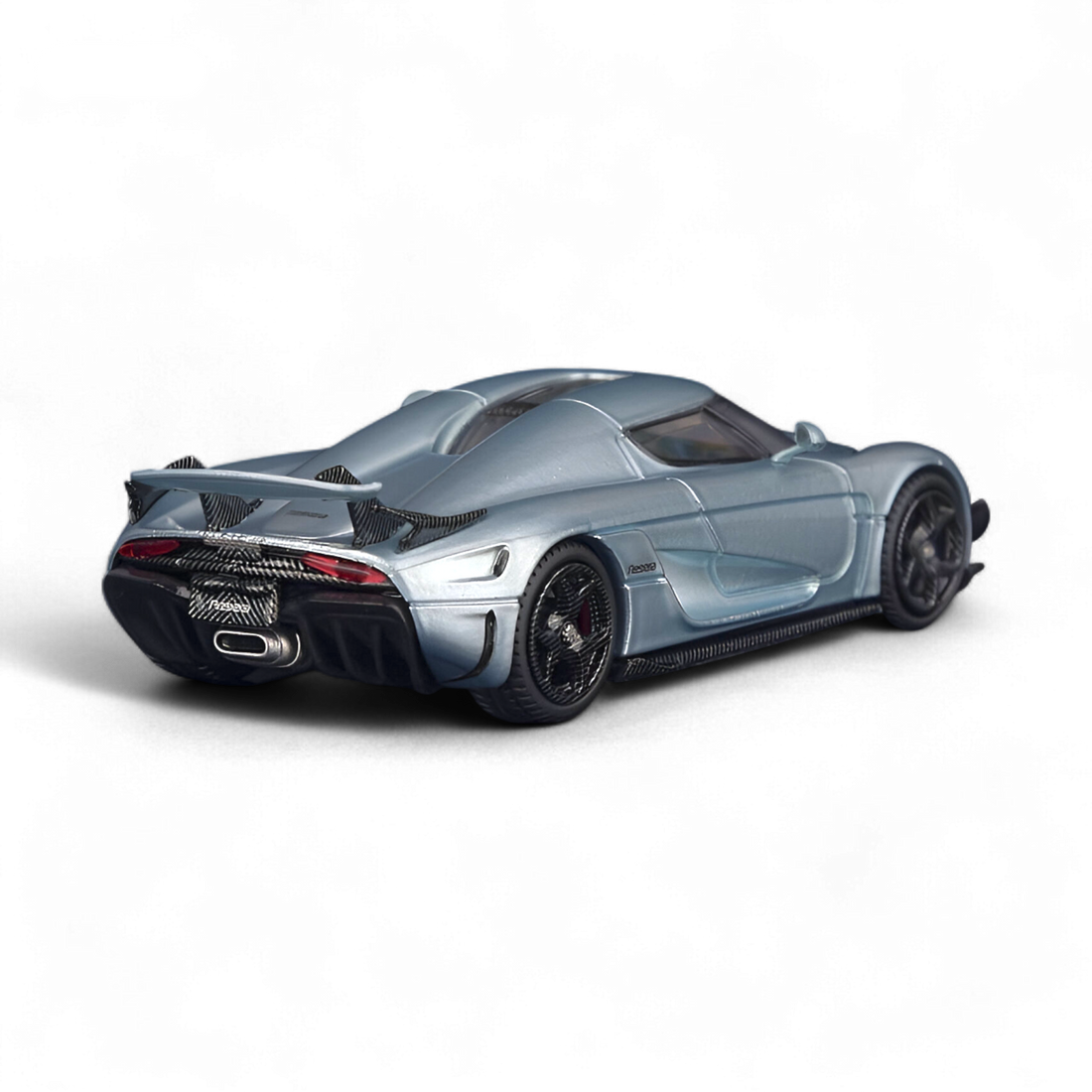 Rear three-quarter view of the SC ART Koenigsegg Regera Glacier Blue 1:64 diecast model showcasing the aerodynamic bodywork, rear wing, and detailed carbon fiber finish.